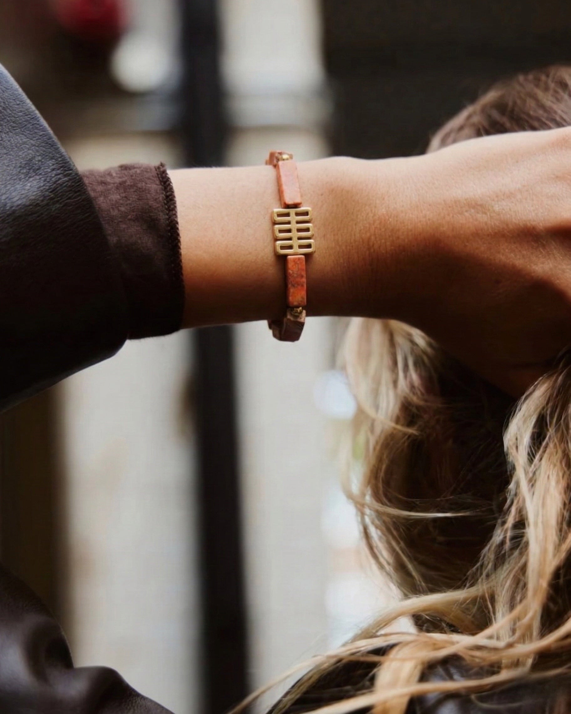 Close-up of a person wearing a gold bracelet with a blurred background
