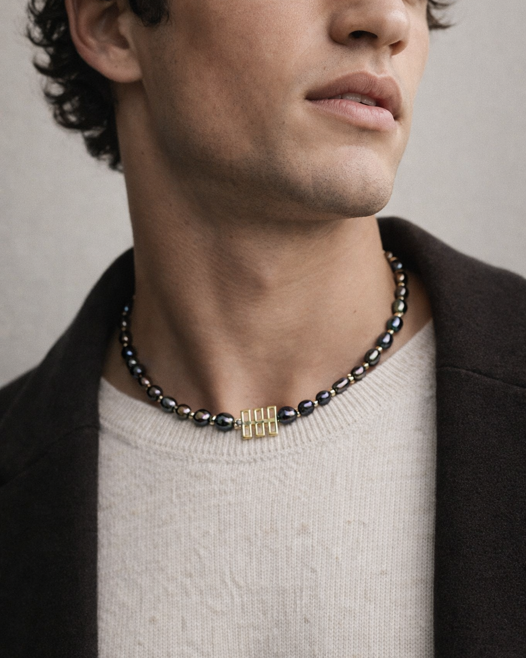 Man wearing a necklace with a neutral background